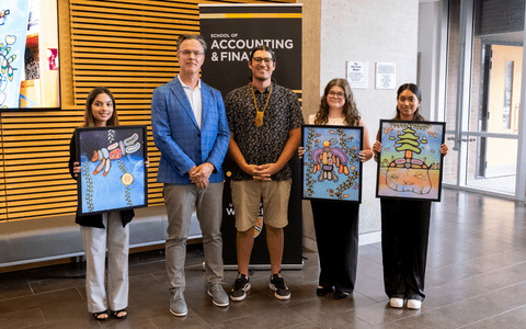 Blake Philips and Kyle Jodicke with three students holding prints of the mural