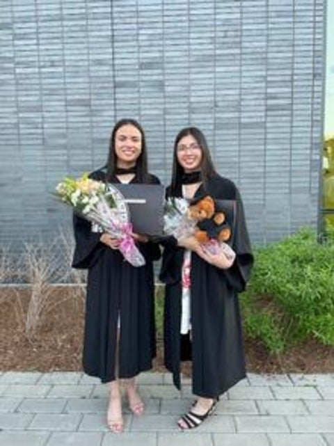 Stephanie and Jessica Nguyen holding diplomas and flowers