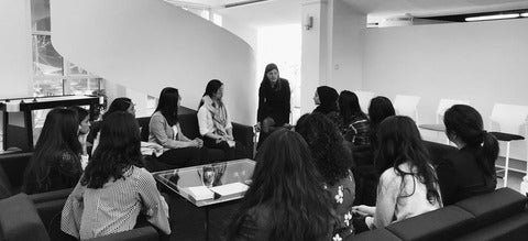 A black-and-white photo of a group of female students having a meeting in a lounge