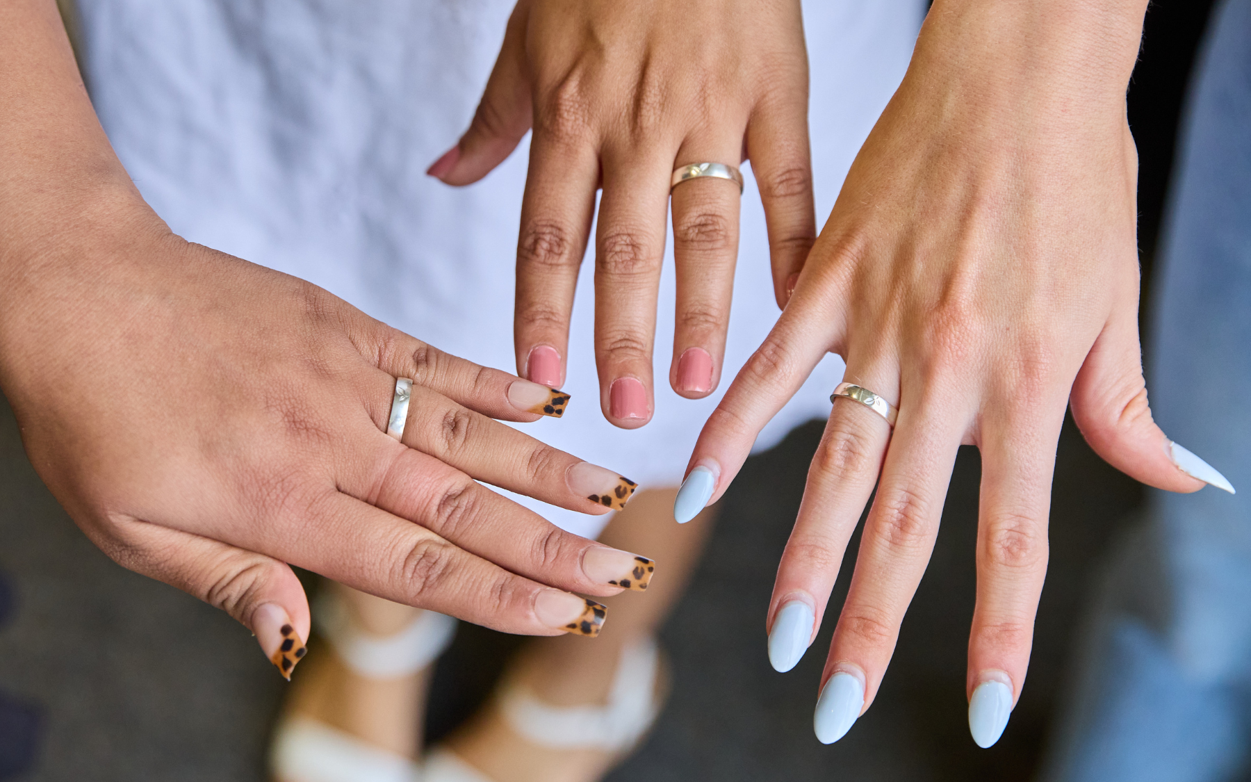 A closeup of three SFM graduate hands wearing their class rings