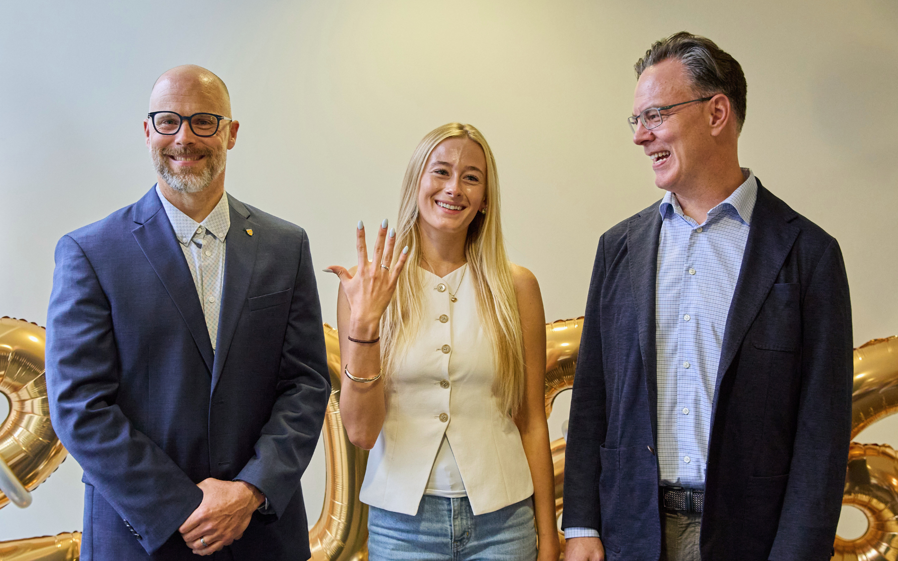 Blake Phillips and Michael wood pose for a photo with an SFM graduate who is showing off her class ring.