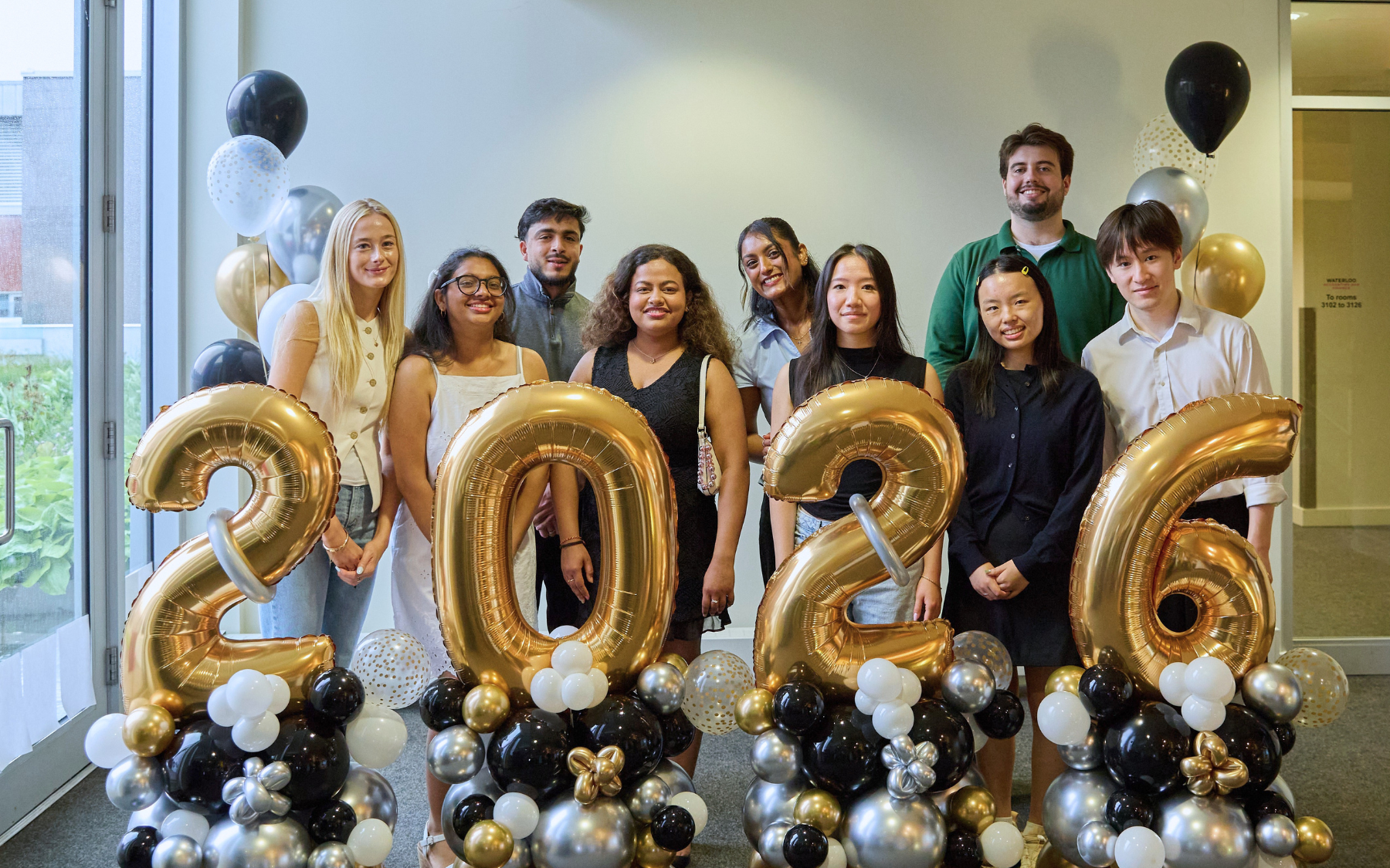 The first cohort of SFM graduates pose with "2026" balloons.