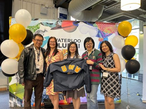 Graduates Michael Chang, Tieu Minh To, Amy Chung, Yollie Leung, and Mandy La-Seto posing with a UW Alumni jacket.