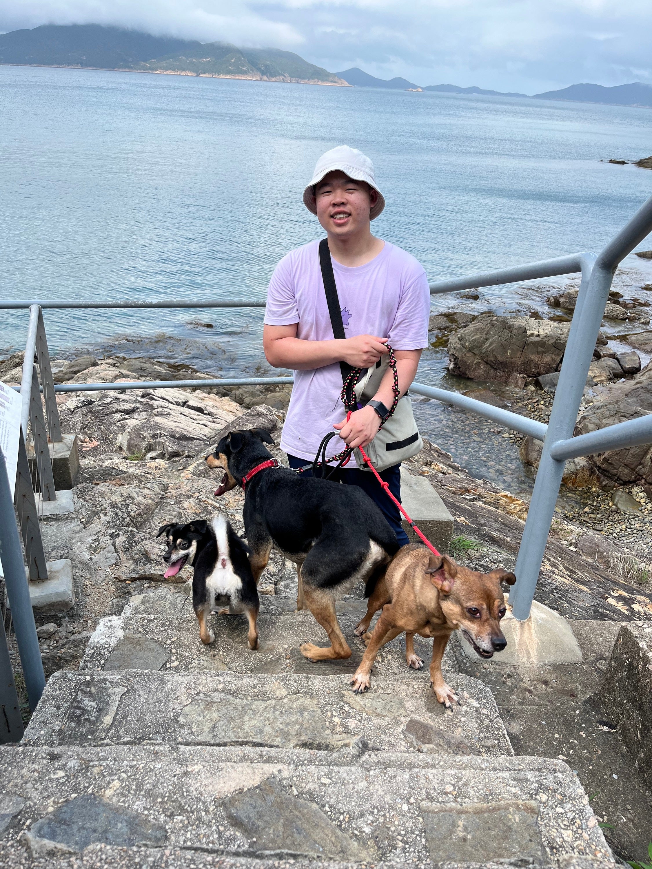 Full body shot of Donald with three dogs in front of a body of water