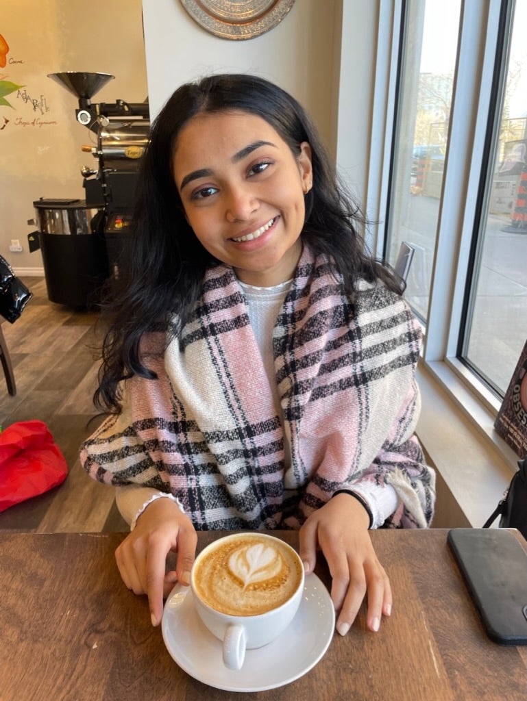 Upper body shot of Hemadri sitting at a cafe with a drink