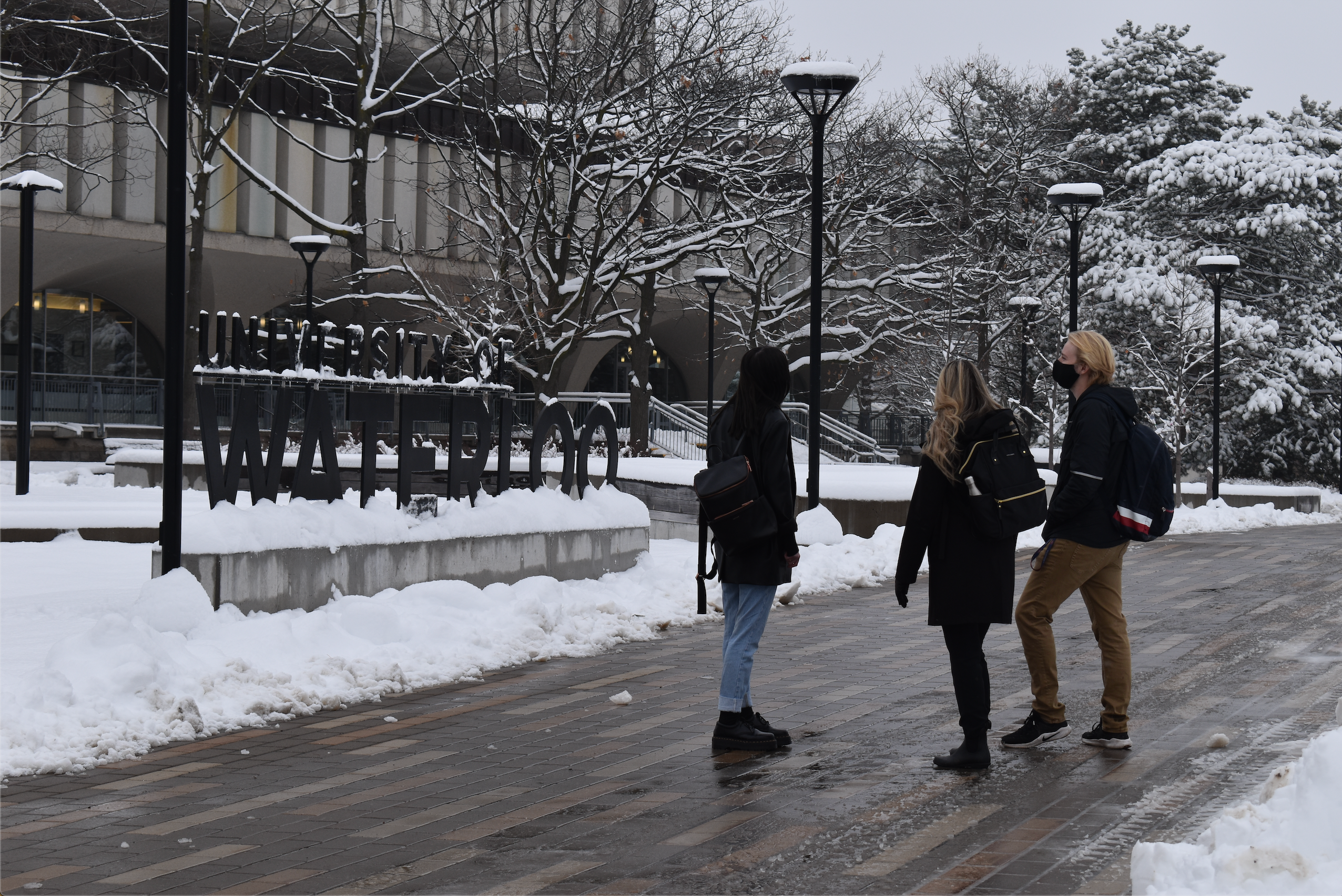 Image of students looking at the University of Waterloo sign