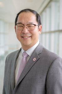 headshot of man in grey suit smiling