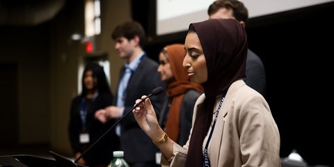 A panel of students in formal wear presenting a slide deck