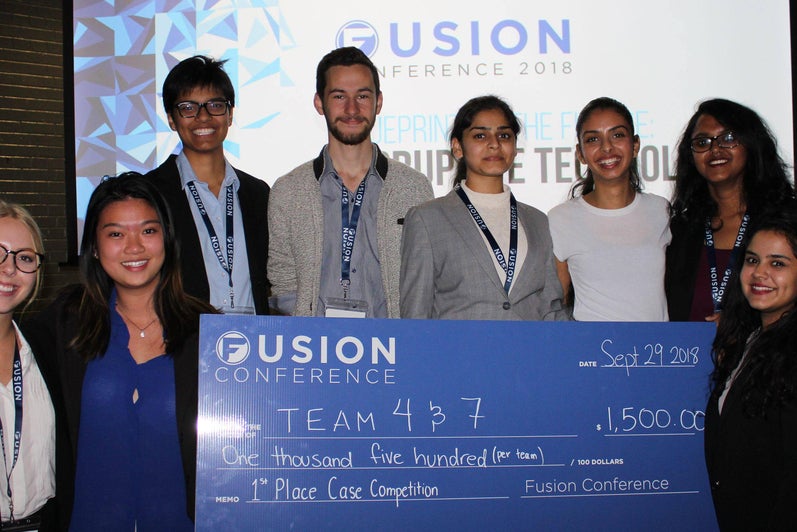 Winners from the Fusion case competition holding a large blue cheque.