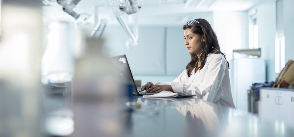 Female working on a computer while sitting at a lab bench.