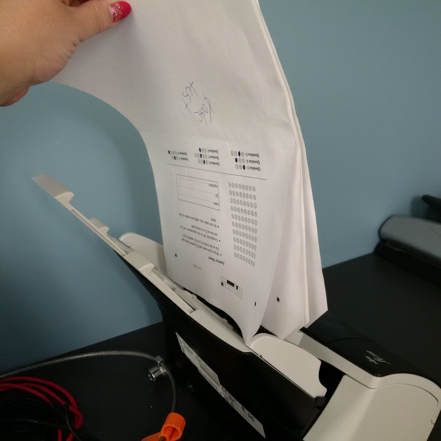 Hand holding the answer sheets upside down in the correct orientation for scanning.