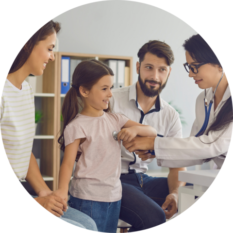 A young child receiving medical treatment beside her parents