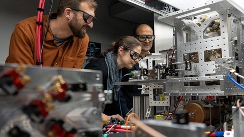 Roger Melko, Crystal Senko and Rajibul Islam looking at their ion trapping quantum computer