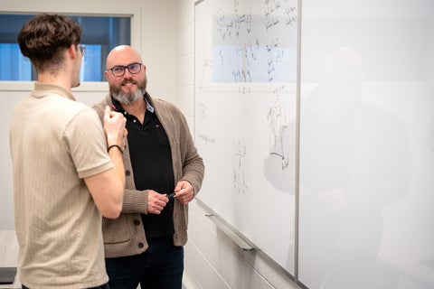 Travis Craddock and a graduate student discussing research at a whiteboard