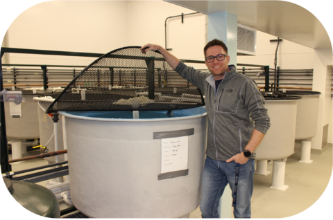 Paul Craig holding up the net covering a large fish tank