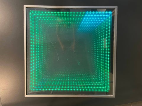 Optics display of a square infinity mirror with a metallic frame.