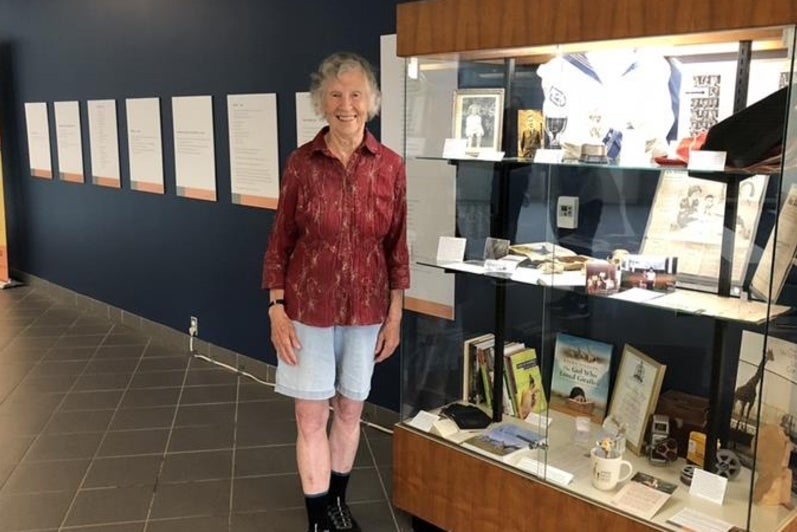 Anne Dagg standing in front of a display case for her exhibit.