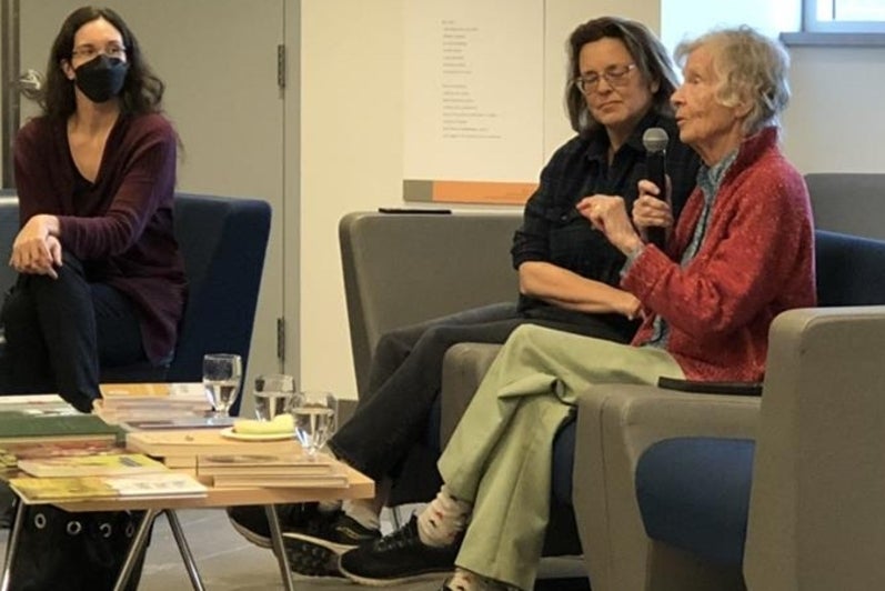 Anne Dagg speaking at her exhibit event, sitting on couches with two other guests.