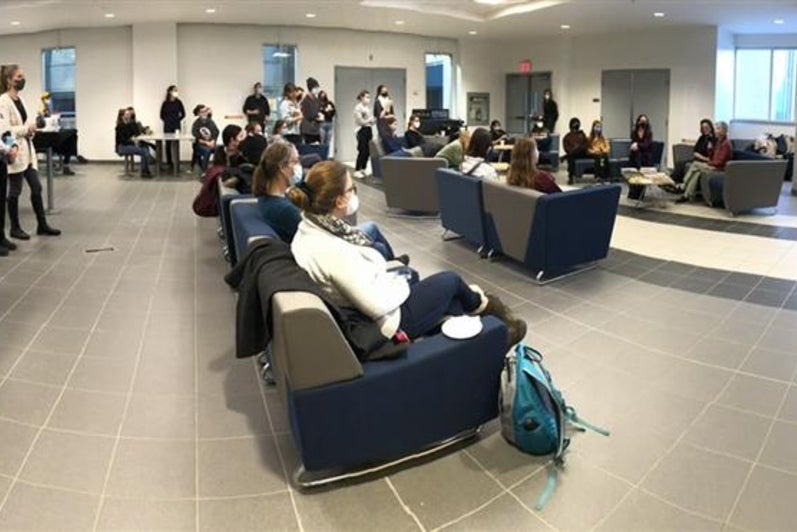 Anne Dagg speaking at her exhibit to a large crowd in an open space.