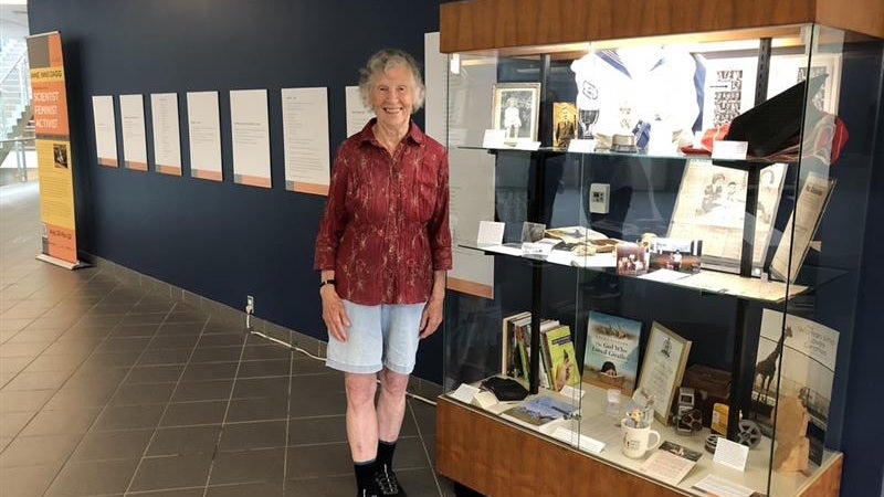 Anne Dagg standing in front of a display case for her exhibit.