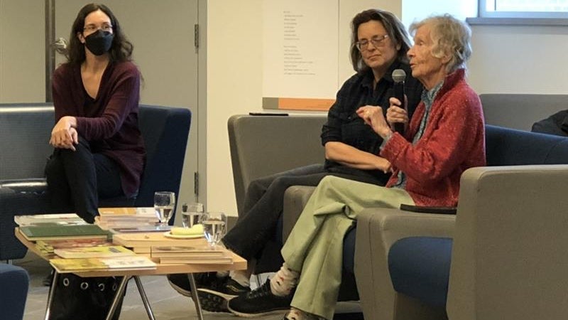 Anne Dagg speaking at her exhibit event, sitting on couches with two other guests.