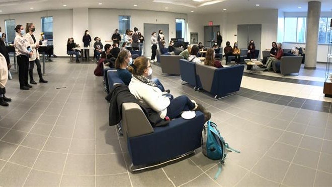 Anne Dagg speaking at her exhibit to a large crowd in an open space.