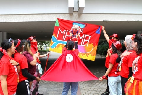 red 'mermagma' orientation leaders posing with team flag