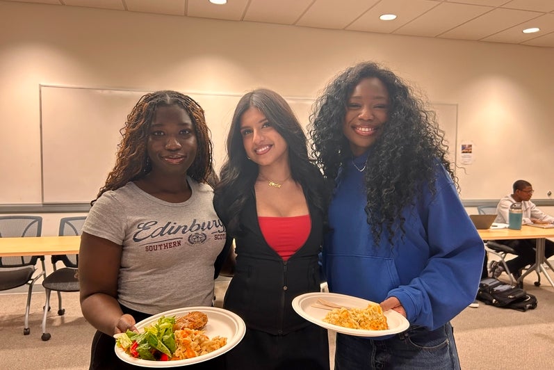 3 students posing with plates of food