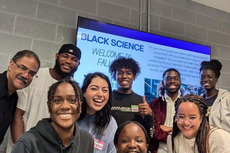 Black science members huddled together smiling