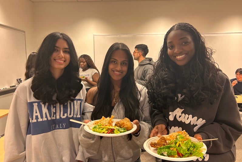 3 students posing with plates of food