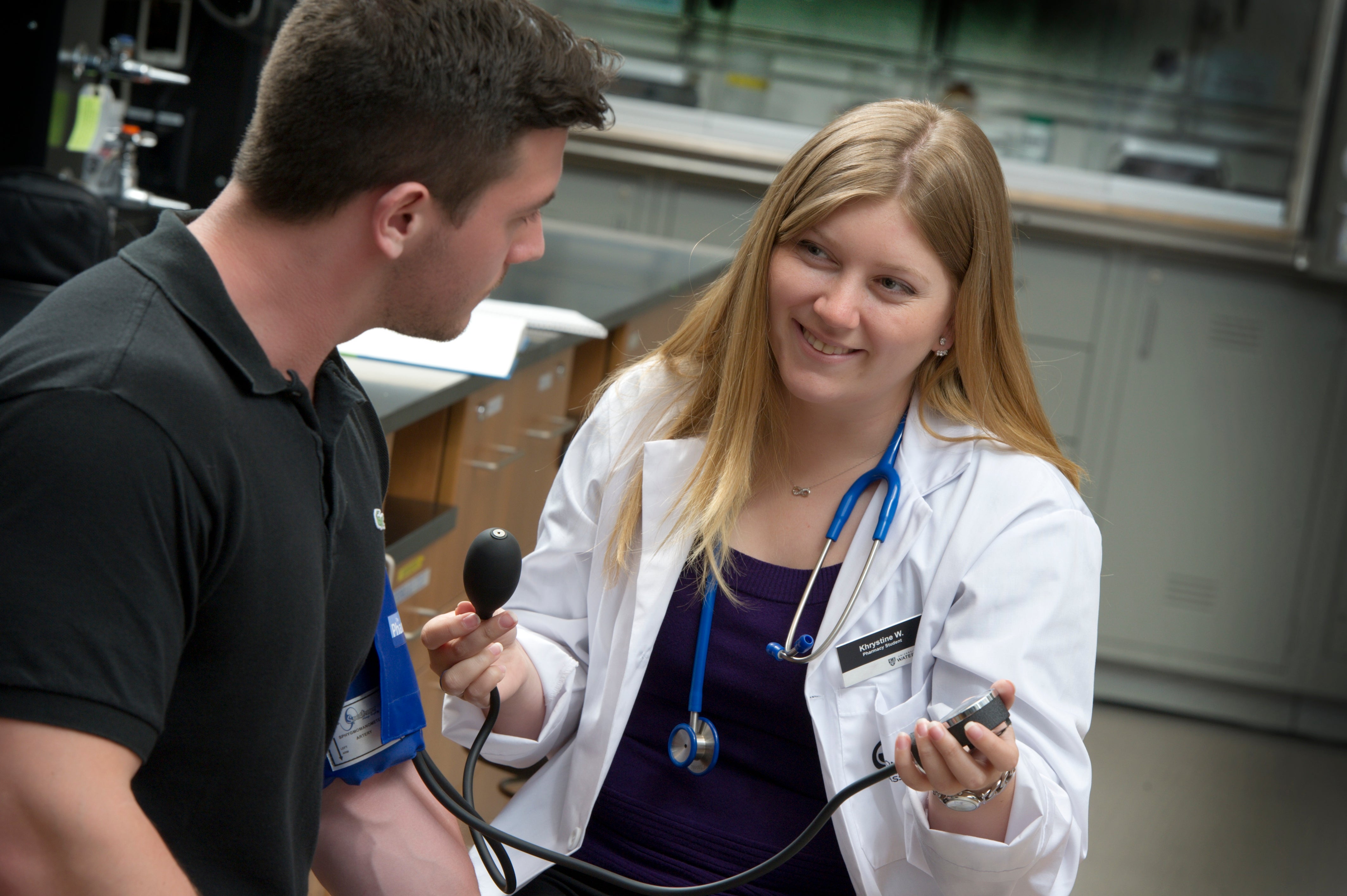 Student in lab coat taking someone's blood pressure.