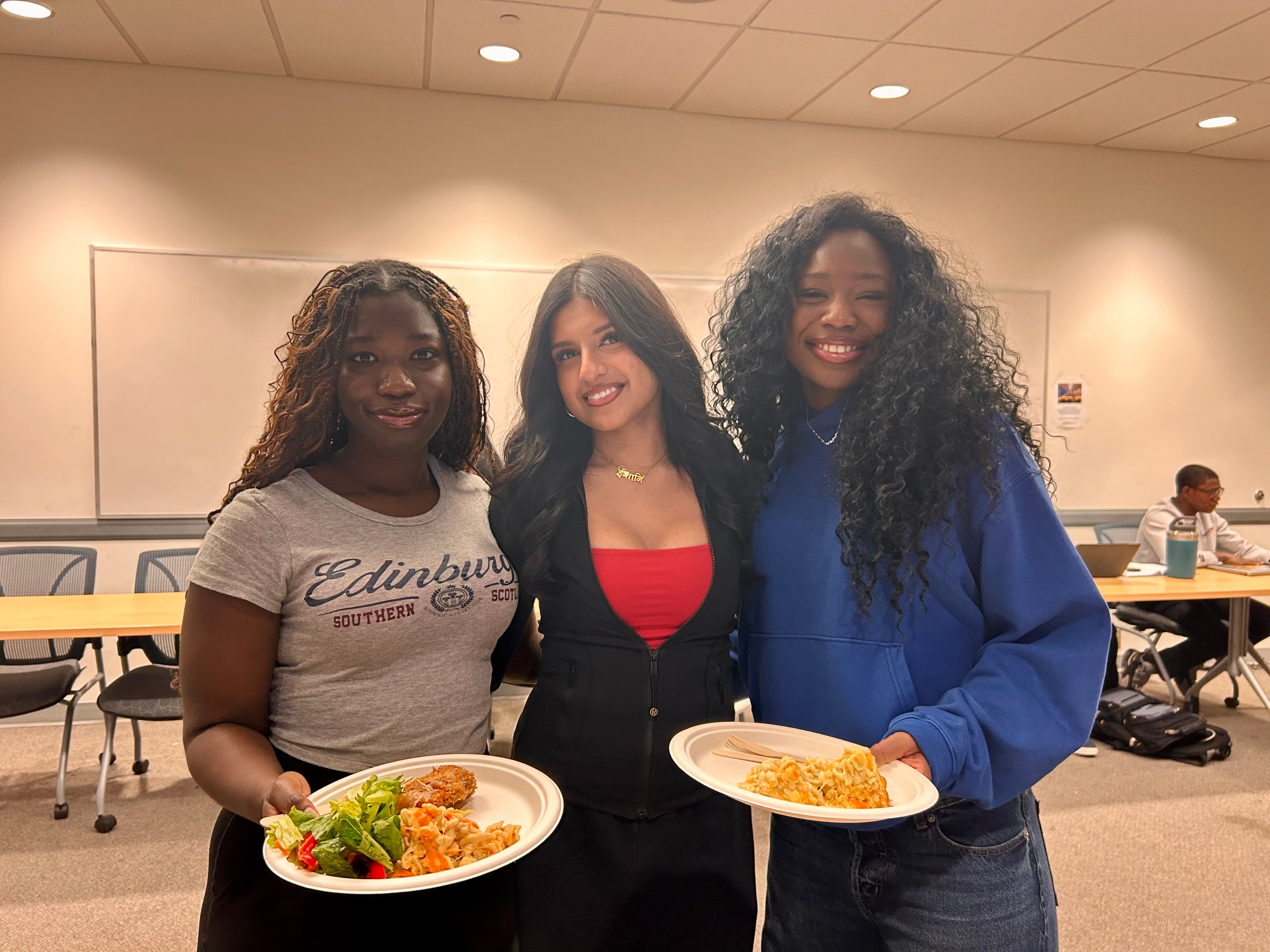 3 students posing with plates of food