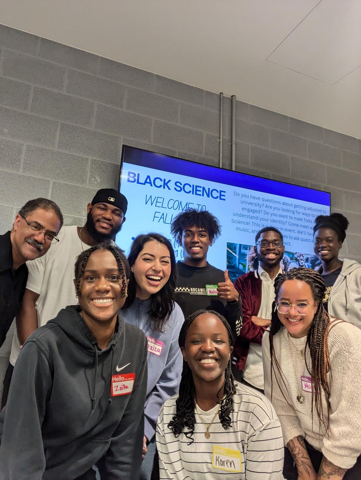 Black science members huddled together smiling