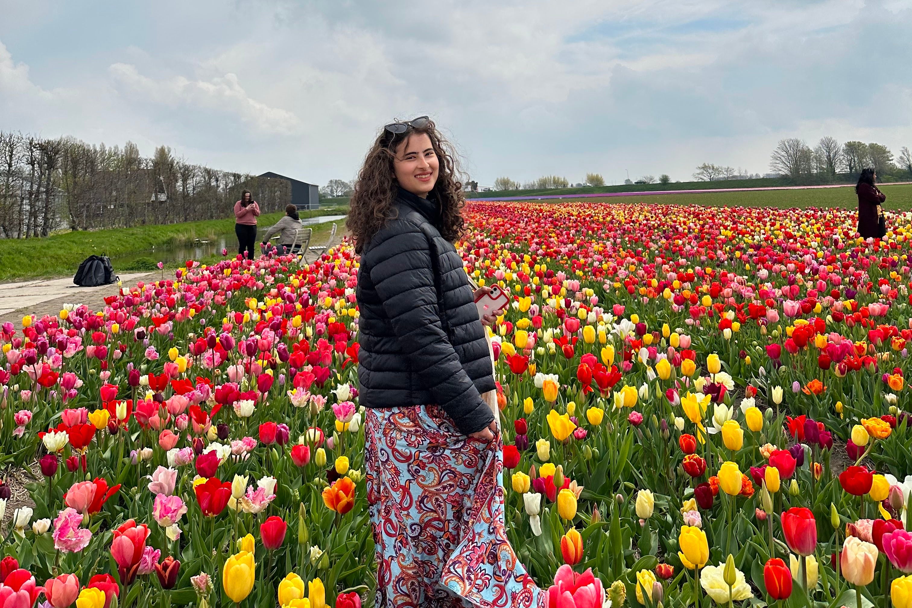 A photo of a science student standing infront of tulips in the Netherlands