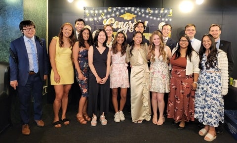 Chemistry students standing in front of a "Congrats grad" banner celebrating convocation