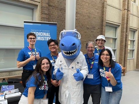 A group of science students with cobalt the dinosaur in the middle.