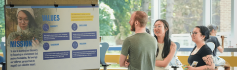 Three sutdents looking at a poster with Waterloo Science's mission and value statements.