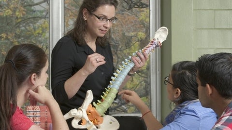 Vivian Dayeh teaching a group of students using a skeletal model.