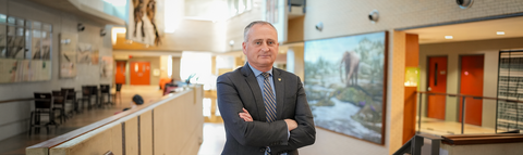 Dean Chris Houser posing with his arms crossed in the Earth Sciences museum at the University of Waterloo.