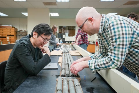 Professor Chris Yakymchuk assisting a graduate student with mineral deposits in a lab.