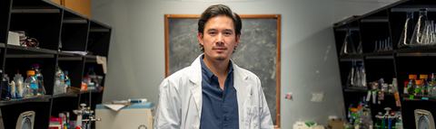 David Sychantha wearing a white lab coat in a chemistry lab.