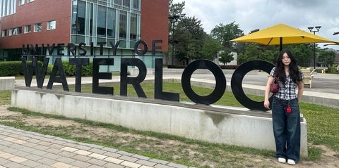 Dorathy standing next to the University of Waterloo sign on campus.