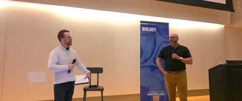 Travis Craddock and Dale Martin talking with microphones at the front of a lecture hall