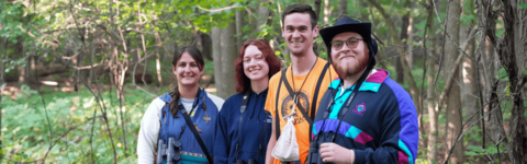 Four students conducting field work in a forest.