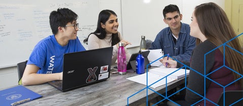 Four graduate students chatting around a table.