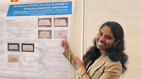 Megala Ramasamy standing in front od research presentation board