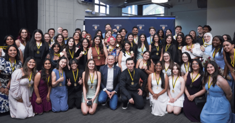 A large group of Ideal Scholars holding their medals in front of a University of Waterloo banner. Dean Chris Houser is in the centre.