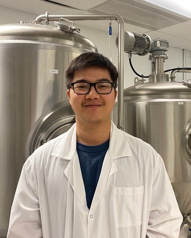 Mathew Li standing in front of reaction tanks