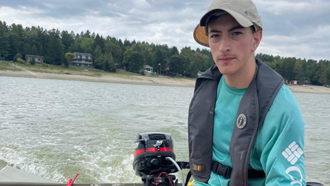Joey Ruck is steering a boat on a lake.