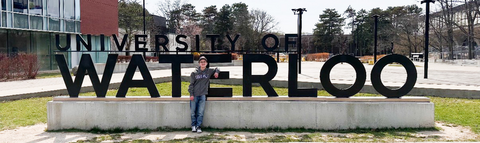 Luca Roy standing in front of the University of Waterloo sign